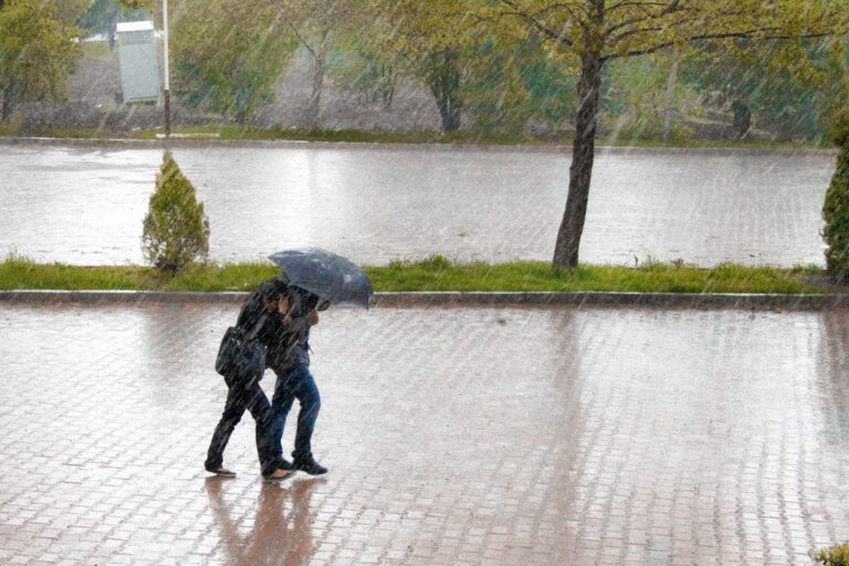 "Couple walking under an umbrella in rain, highlighting Back-to-School Health Insurance Tips for College Students."