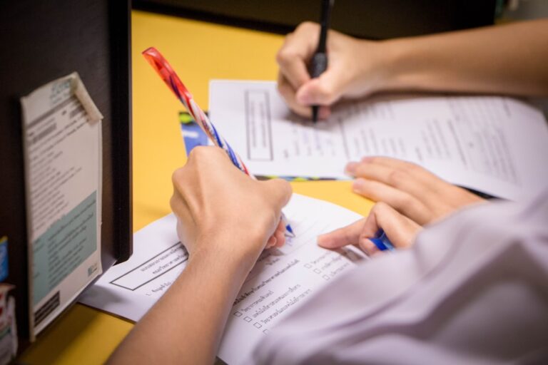 Hands writing on papers, representing inclusive employment and insurance benefits that empower all workers.