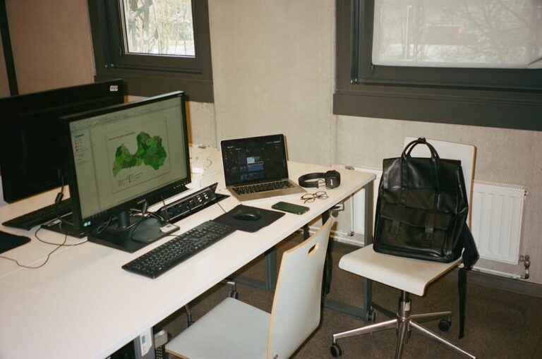 "Workspace setup to protect your business income with interruption insurance, featuring monitors, laptop, and essential tools."