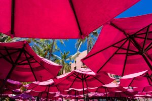 "Colorful pink umbrellas shade a relaxing scene, highlighting ways to protect your retirement savings from market volatility."
