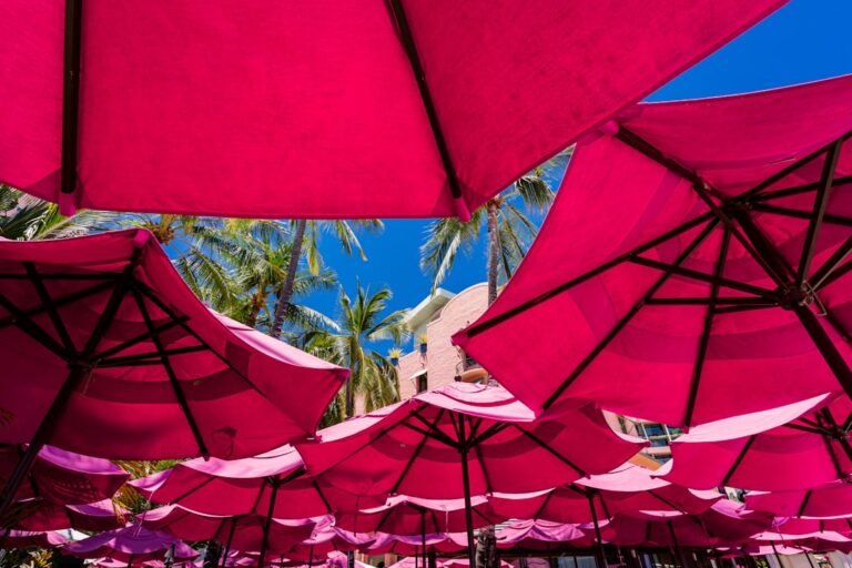 "Colorful pink umbrellas shade a relaxing scene, highlighting ways to protect your retirement savings from market volatility."