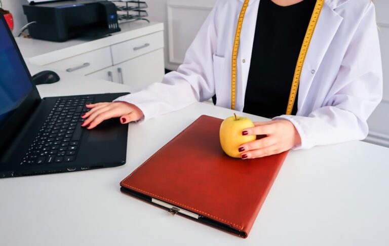 "Doctor with an apple and laptop, exploring HMO insurance: benefits, costs, and coverage."