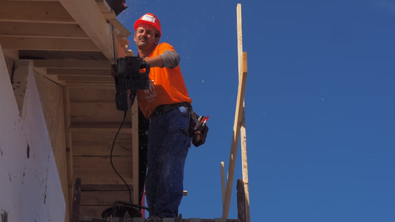 Professional contractor in safety gear, inside a warehouse, emphasizing Workers' Compensation for Contractors compliance