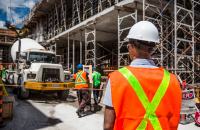 a man in safety vest and hardhats standing in front of a construction site