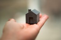 A hand holding a small model house, representing homeowners insurance basics and what your policy covers.