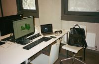 "Workspace setup to protect your business income with interruption insurance, featuring monitors, laptop, and essential tools."