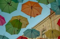Colorful umbrellas hanging overhead symbolize protection in "Why Life Insurance Matters for Parents This School Year."